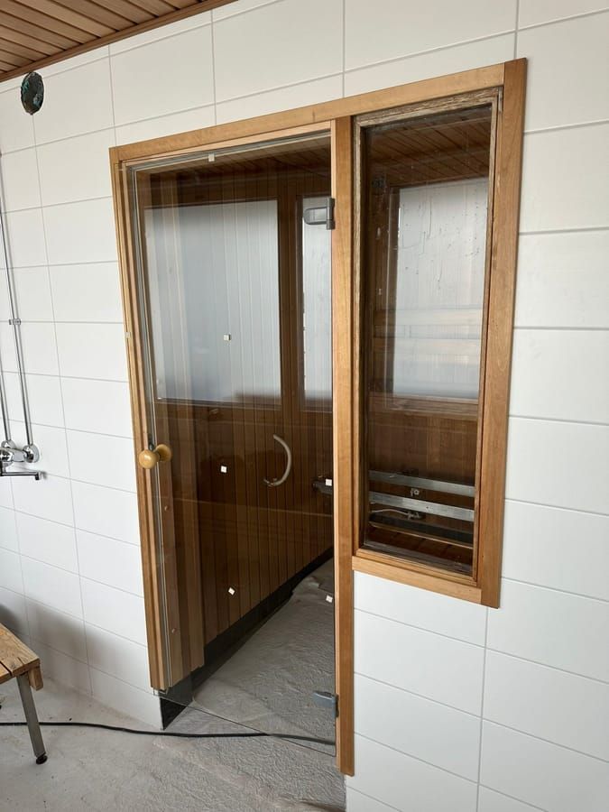 Käpylän taloyhtiön saunan uusi lasiovi pesuhuoneesta katsottuna