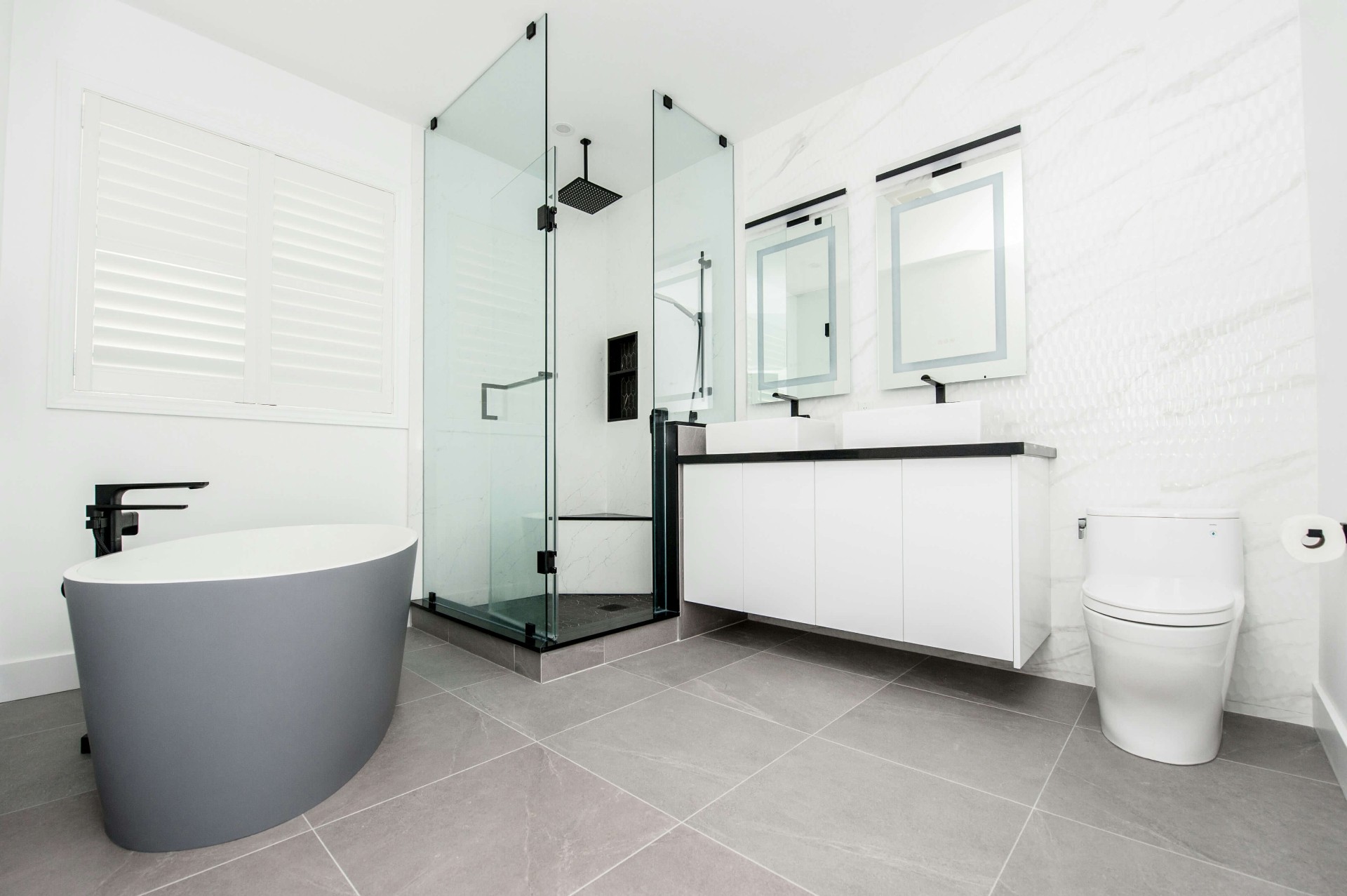 Moderni kylpyhuone Helsingissä remontin jälkeen, harmaat laatat ja lasisuihku